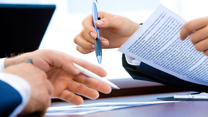sets of hands of two people holding papers and pen review writing content