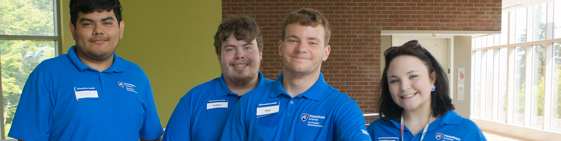 four smiling students in matching NSO leader polo shirts