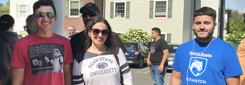 three students in Penn State tee shirts outside an apartment building