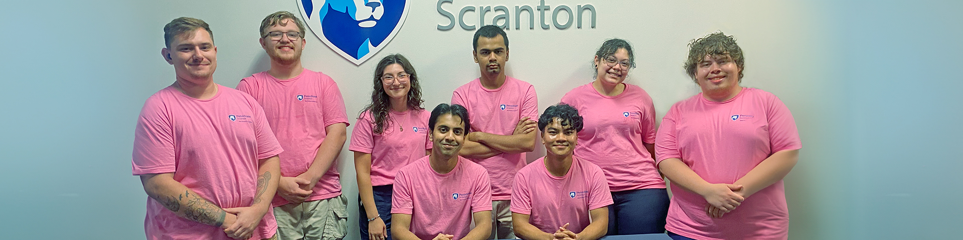 8 smiling students pose in front of penn state scranton sign