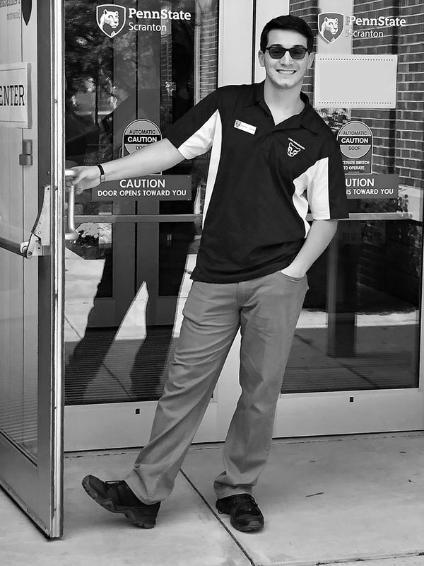 student smiling holding the door open