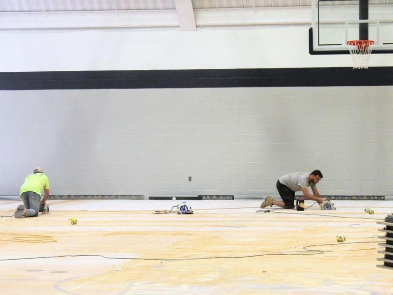 workers sanding and removing floor in the campus gym