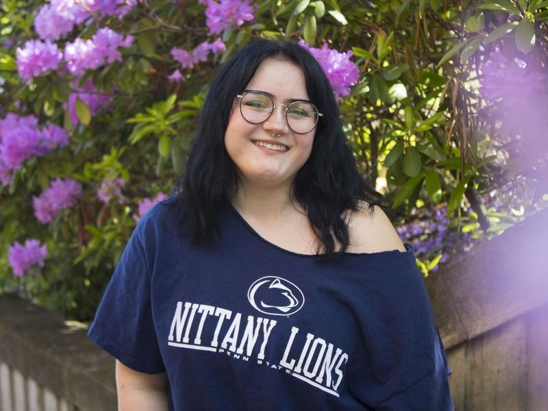 Student smiles in front of flowers