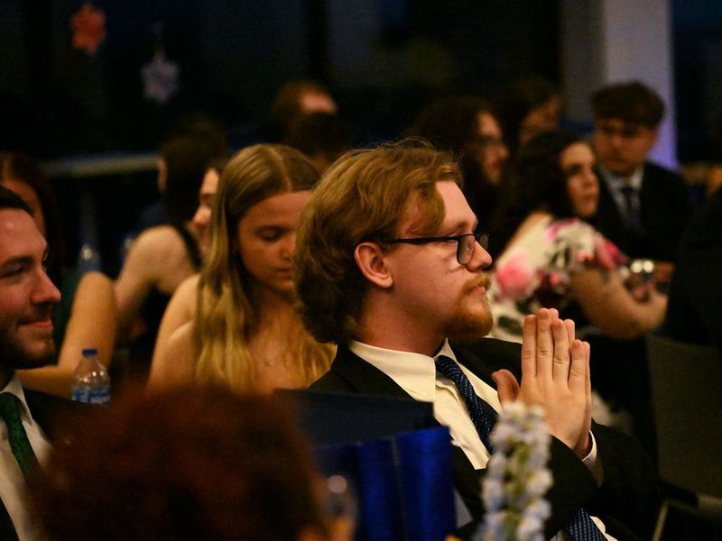 Student dressed in suit and tie sitting in audience