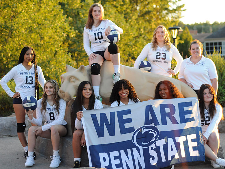 group of women athletes with a we are penn state sign standing by the lion shrine