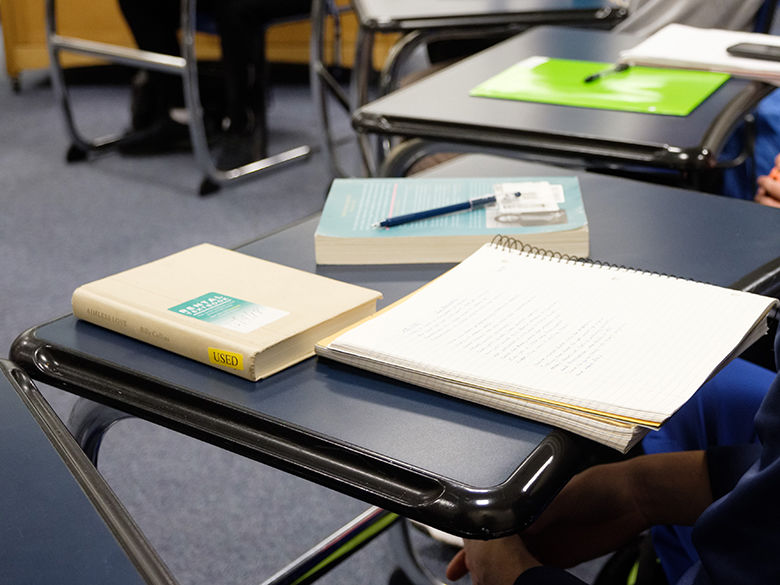 books and tablet on a desk in a classroom