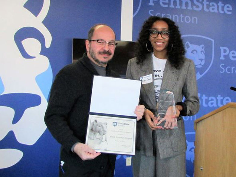 gentleman presents diversity award certificate to a woman