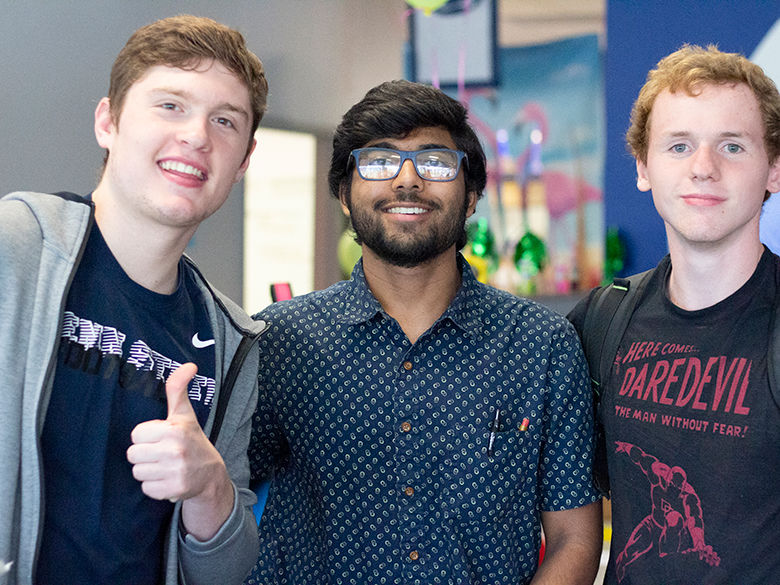 three smiling students give the thumbs up 