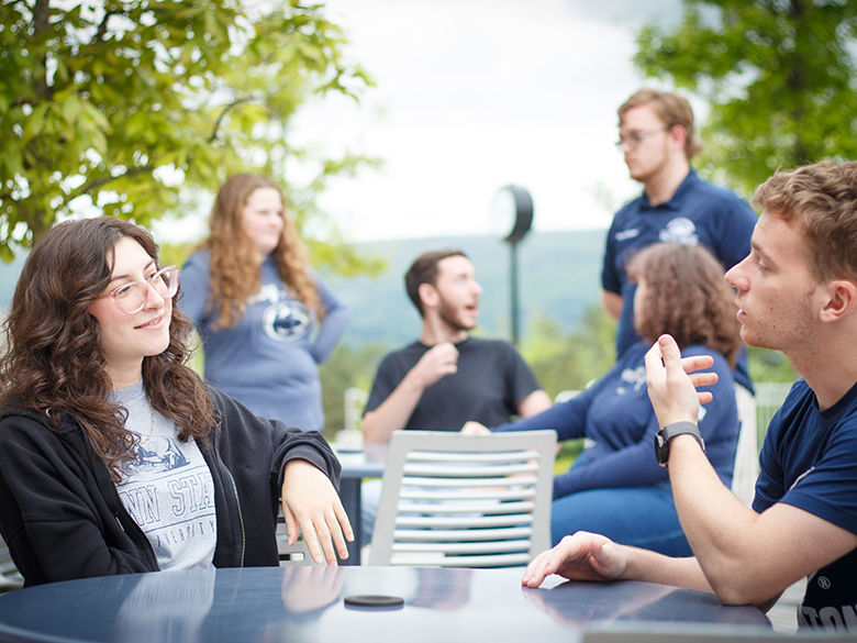 group of students at picnic tables on patio