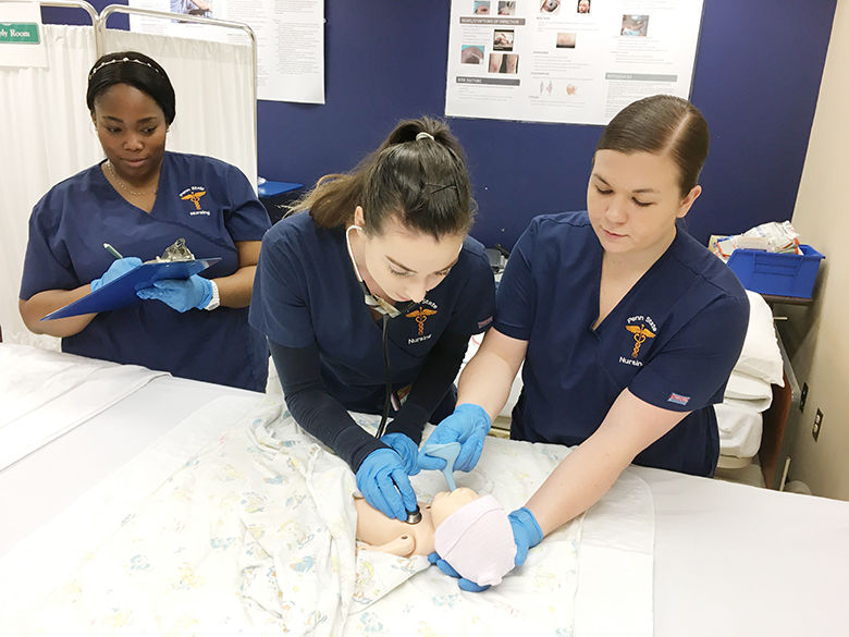 three nursing students practice on infant simulator