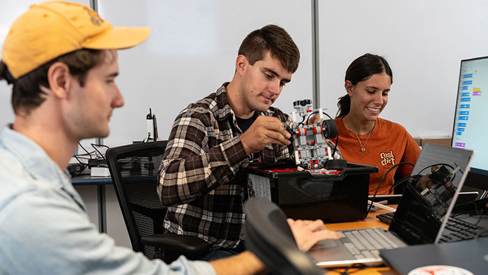 three students work in robotics in engineering class