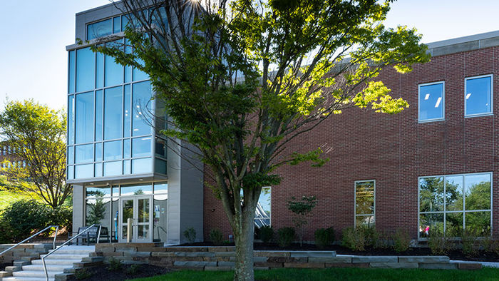 brick building with a glass entry way surrounded by green trees