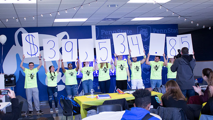 10 students hold large white cards over head revealing total funds raised equaling $39,534.85