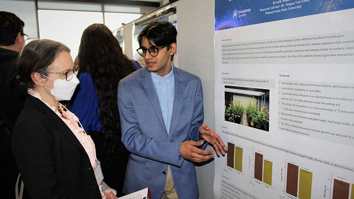 student explains biology poster at research fair