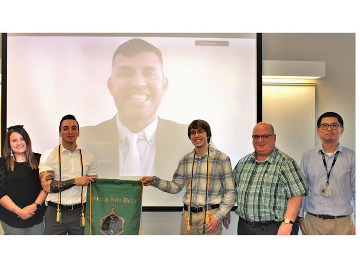 sigma beta delta group posed in front of screen with virtual image of co-inductee Carlos salazar
