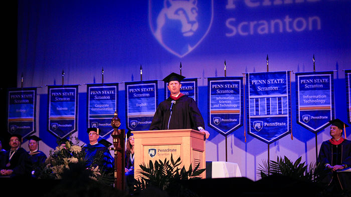 may at podium on stage at a graduation ceremony