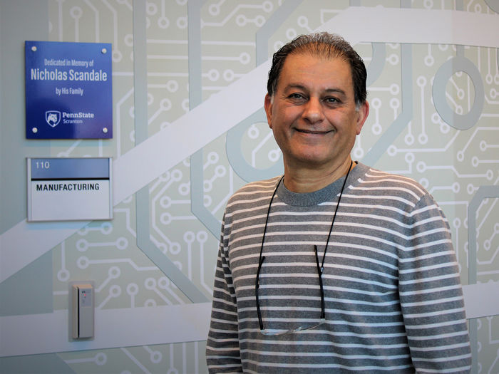 Majid Chatsaz stands at entranceway of the manufacturing lab in the engineering Building