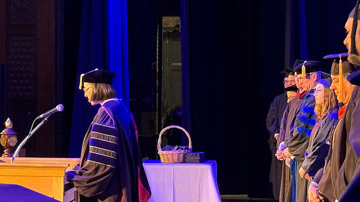 woman wearing graduation cap and gown at podium on stage