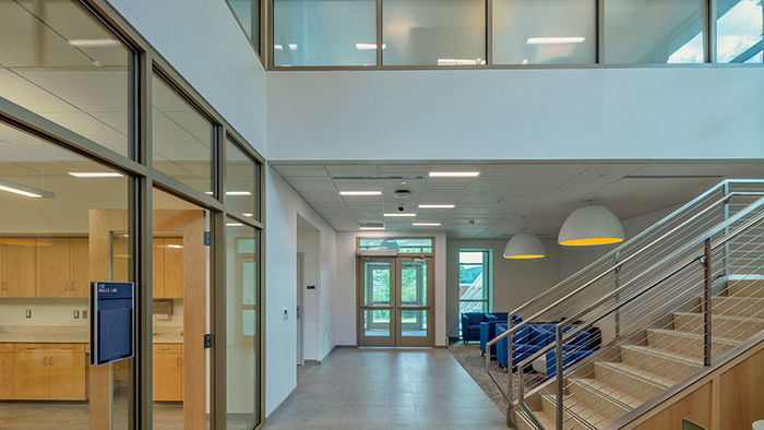 large modern foyer with bright windows, white walls, and stairwell