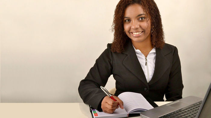 smiling student in a business suit at a laptop