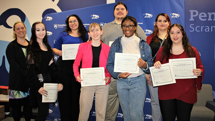 diverse group of eight students smile while holding certificates