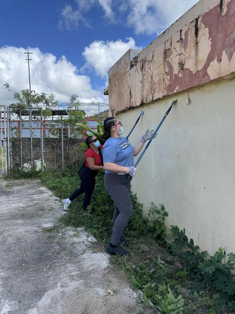 three students clean an outside wall