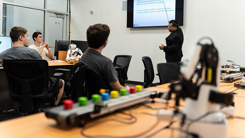 students in class watching teacher use large monitor to cover engineering work