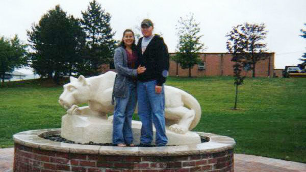 a young couple posing near nittany lion statue