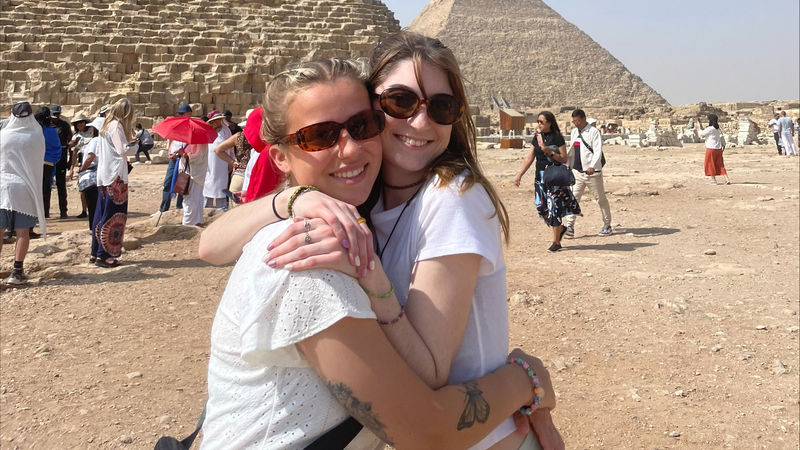 two girls hug in front of pyramids in Egypt
