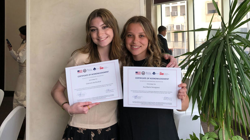 two girls pose with certificates