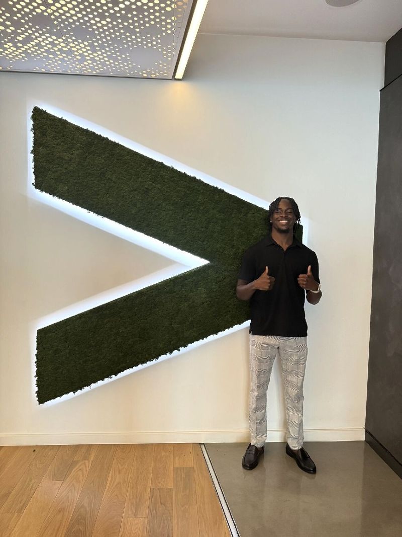 A student gives thumbs up while standing next to an Accenture logo