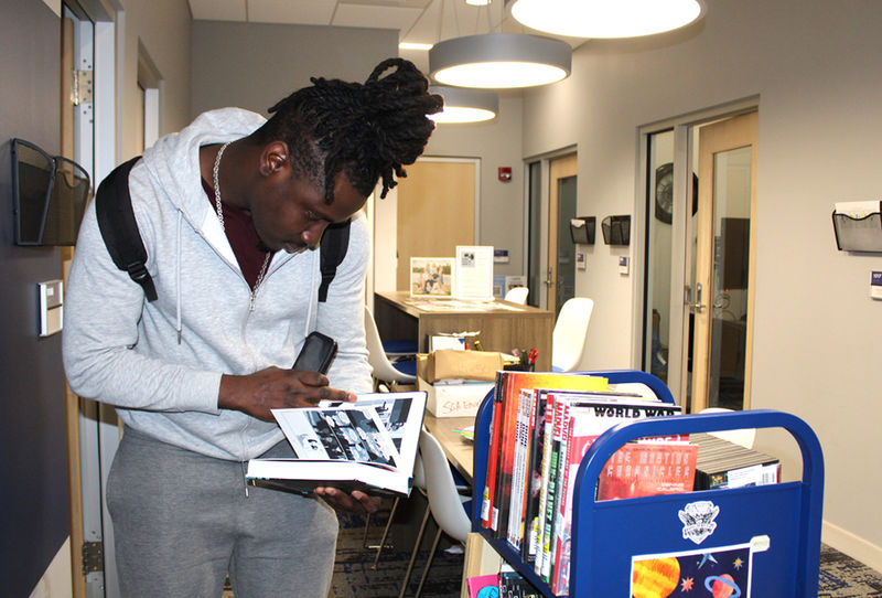Student Jermin Gilbert browses through some of the selections on the science fiction themed library cart.
