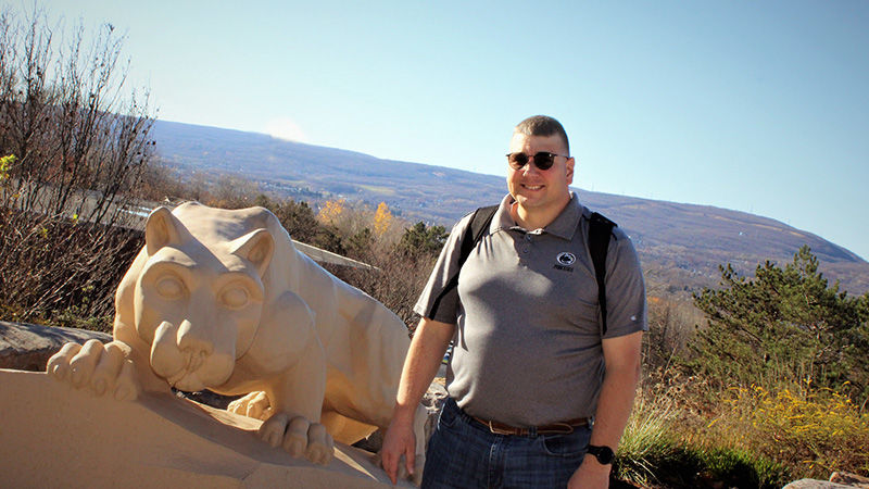 Jayson Zimmerman poses for a picture at the campus Nittany Lion Shrine