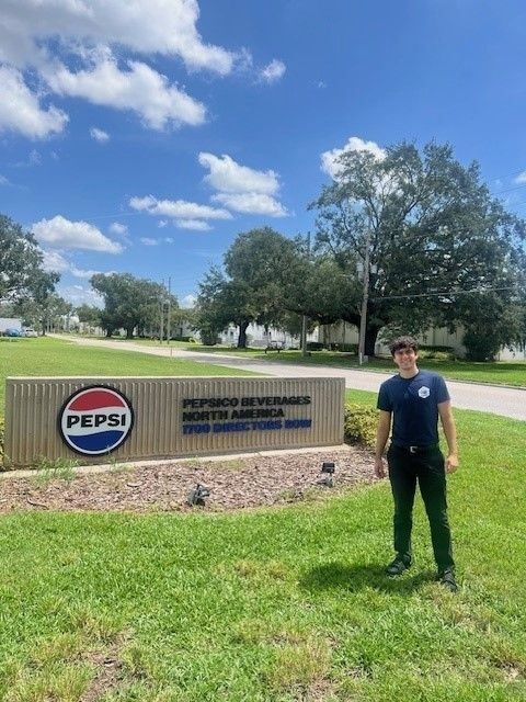 A student stands in front of a PepsiCo sign