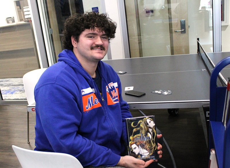 Student Matthew Coggins shows off his book selection from this month's roving Library Cart.