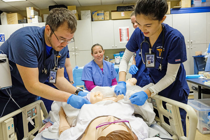 two nursing students practice with mannequin mother and baby