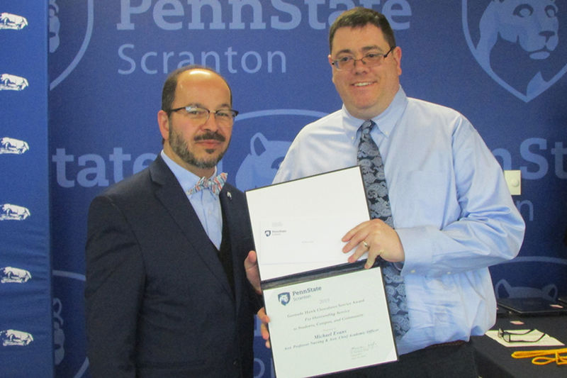 man in suit presents certificate to smiling man