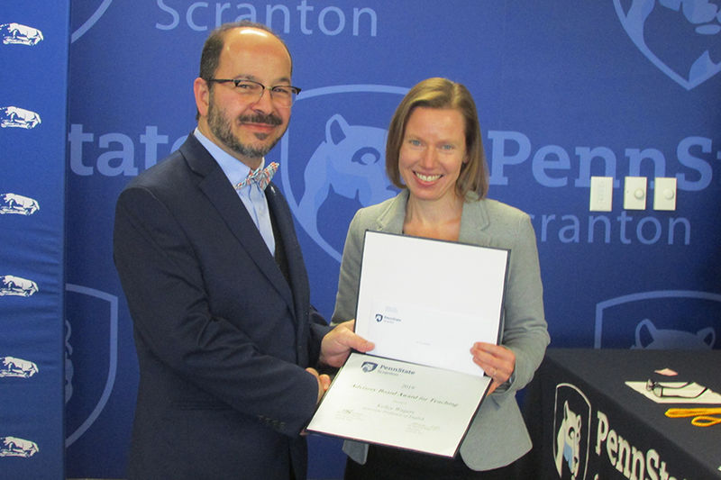 man in suit presents certificate to smiling woman