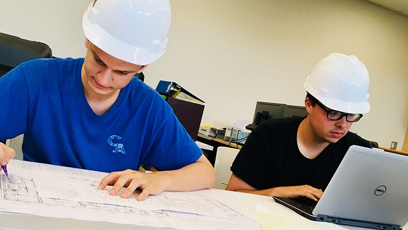 Students in hard hats working on construction plans