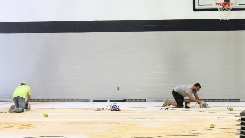 workers sanding and removing floor in the campus gym