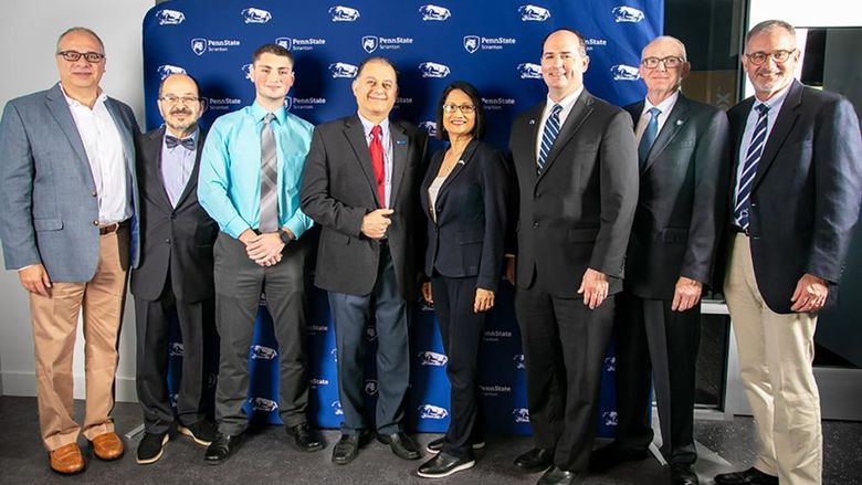 Group of University officials pose for a photo with Penn State Scranton banner backdrop