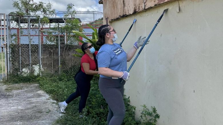 three students clean an outside wall
