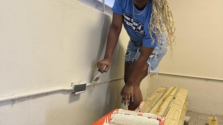 A female student paints a wall 