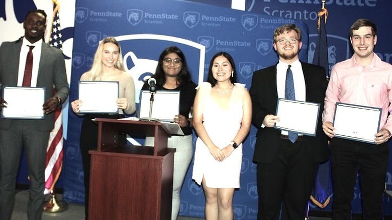 a group of students show off their award certificates onstage at the annual dinner event