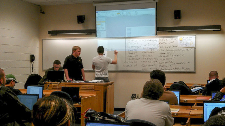 Students stand at a classroom whiteboard as other students watch