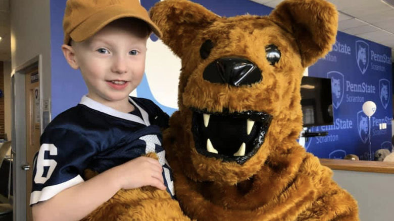 Nittany lion posing for photo with child