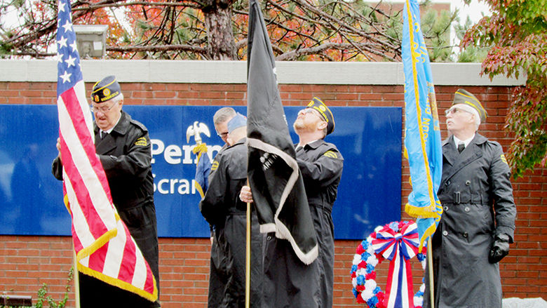 veterans holding US and state flags at veterans day ceremony
