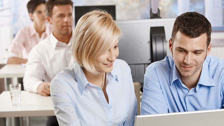 Adult students looking at computers in a classroom setting