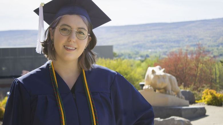 Student wearing commencement regalia and smiling