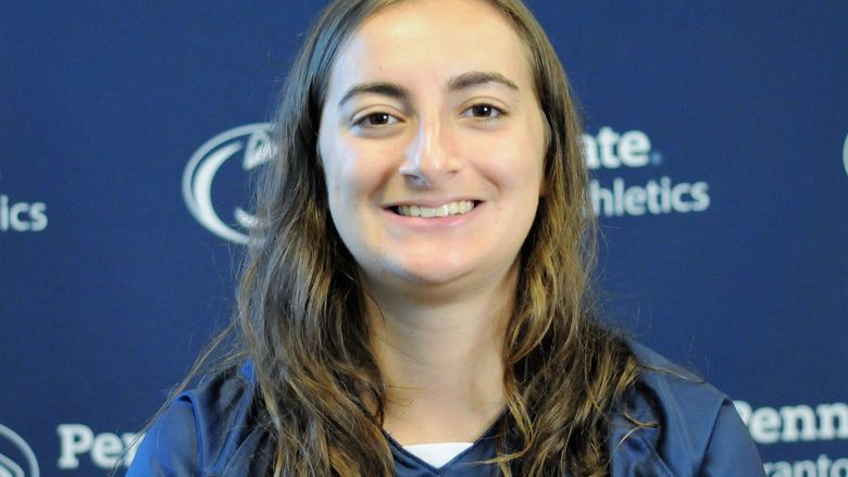 Ashlyn McNally poses for a shot with the PSU Scranton athletics logo as a backdrop
